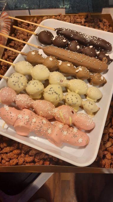 Bunte Spieße mit verschiedenen süßen Kugeln in rosa, gelb, braun und weiß.