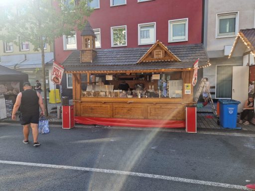 Holzhütte mit Verkaufsständen auf einem Markt in einer urbanen Umgebung.