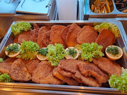 Frittierte Schnitzel auf einem Tablett, garniert mit Salat und Zitronenscheiben.