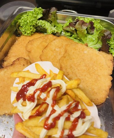 Ein Teller mit frittiertem Hähnchen, Pommes frites und Salat.