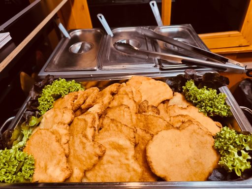 Panierte Schnitzel auf einem Tablett, umgeben von frischem Salat.
