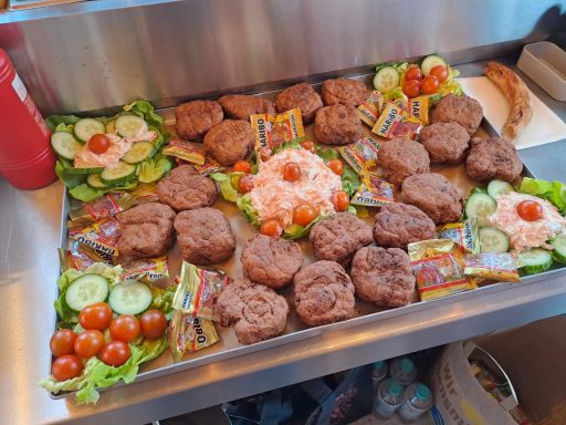 Ein Tablett mit Fleischbällchen, Gemüse und Saucenarrangements.
