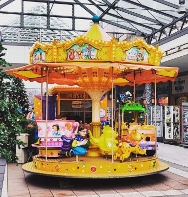 Bunte Karussell mit Figuren, steht in einem Einkaufszentrum.