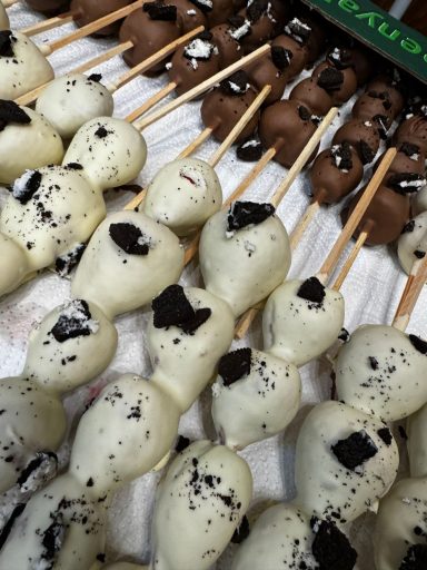 Weiße und braune Schokoladen-Lollis mit Keksen auf Holzspießen.